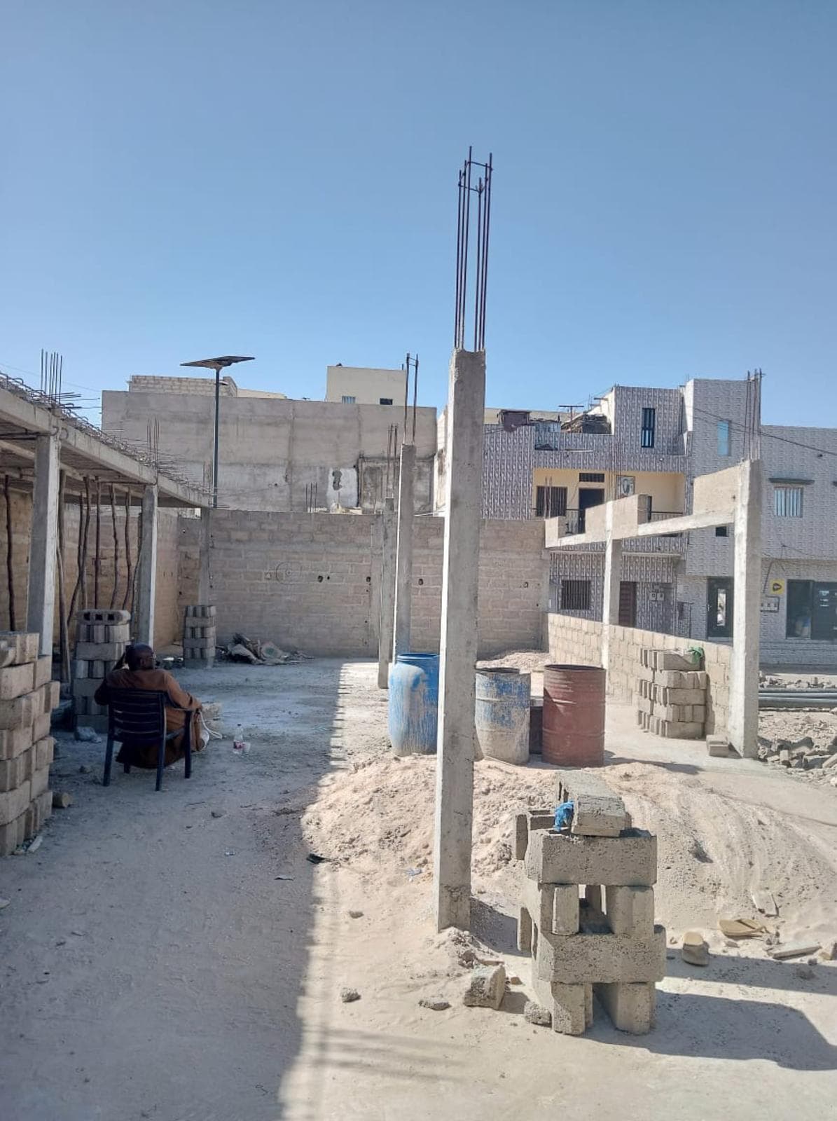 Chantier de construction en cours : murs en parpaings et poteaux de béton
